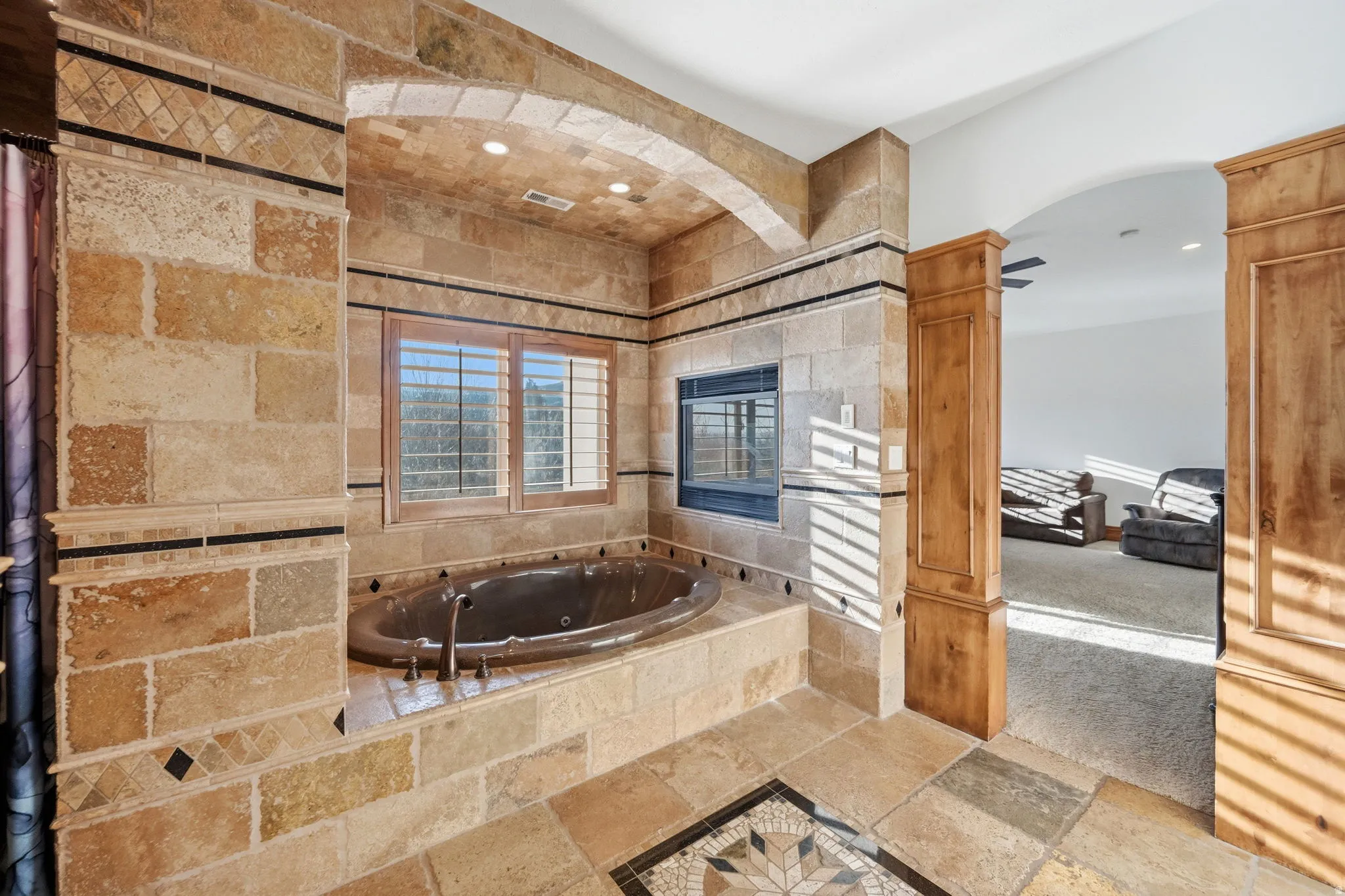 Full bathroom featuring stone tile flooring, a jetted tub, and carpet floors