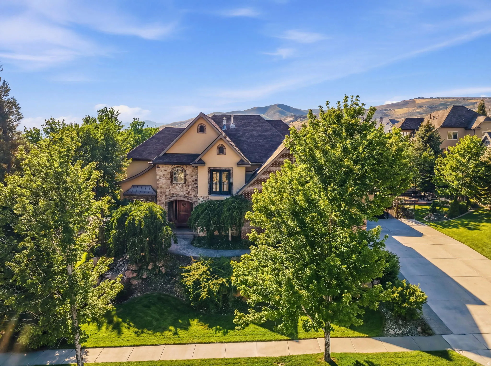 View of front of property featuring stucco siding, stone siding, and a front lawn