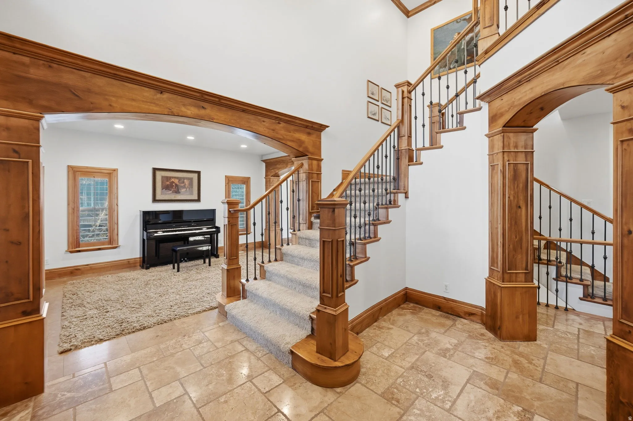 Stairway featuring arched walkways, decorative columns, stone tile flooring, a high ceiling, and recessed lighting