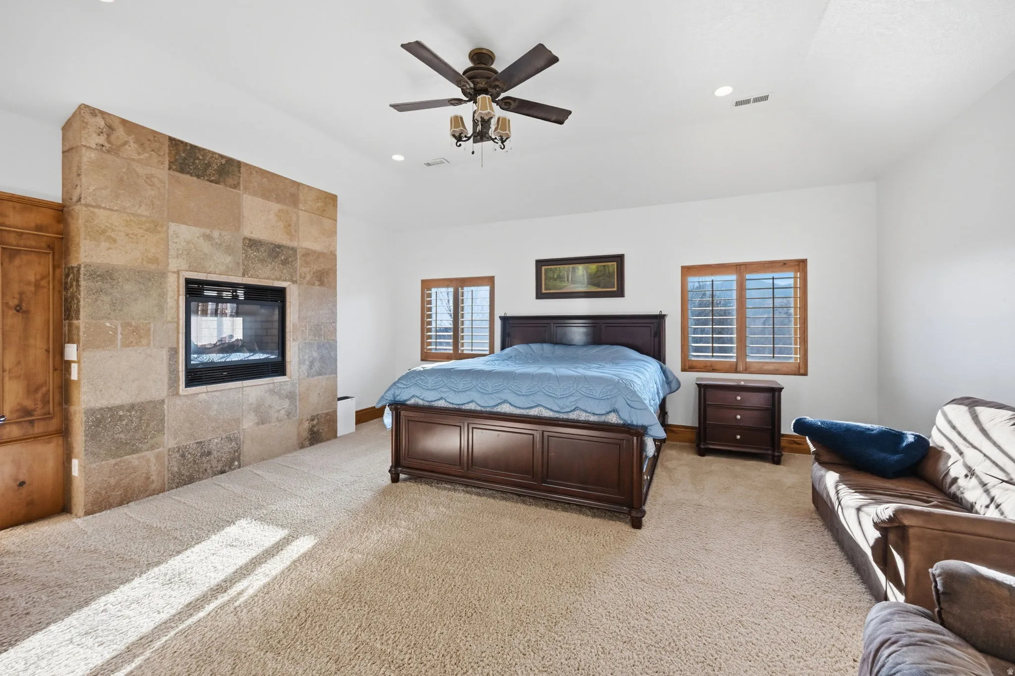 Bedroom with light colored carpet, recessed lighting, a ceiling fan, a tiled fireplace, and vaulted ceiling