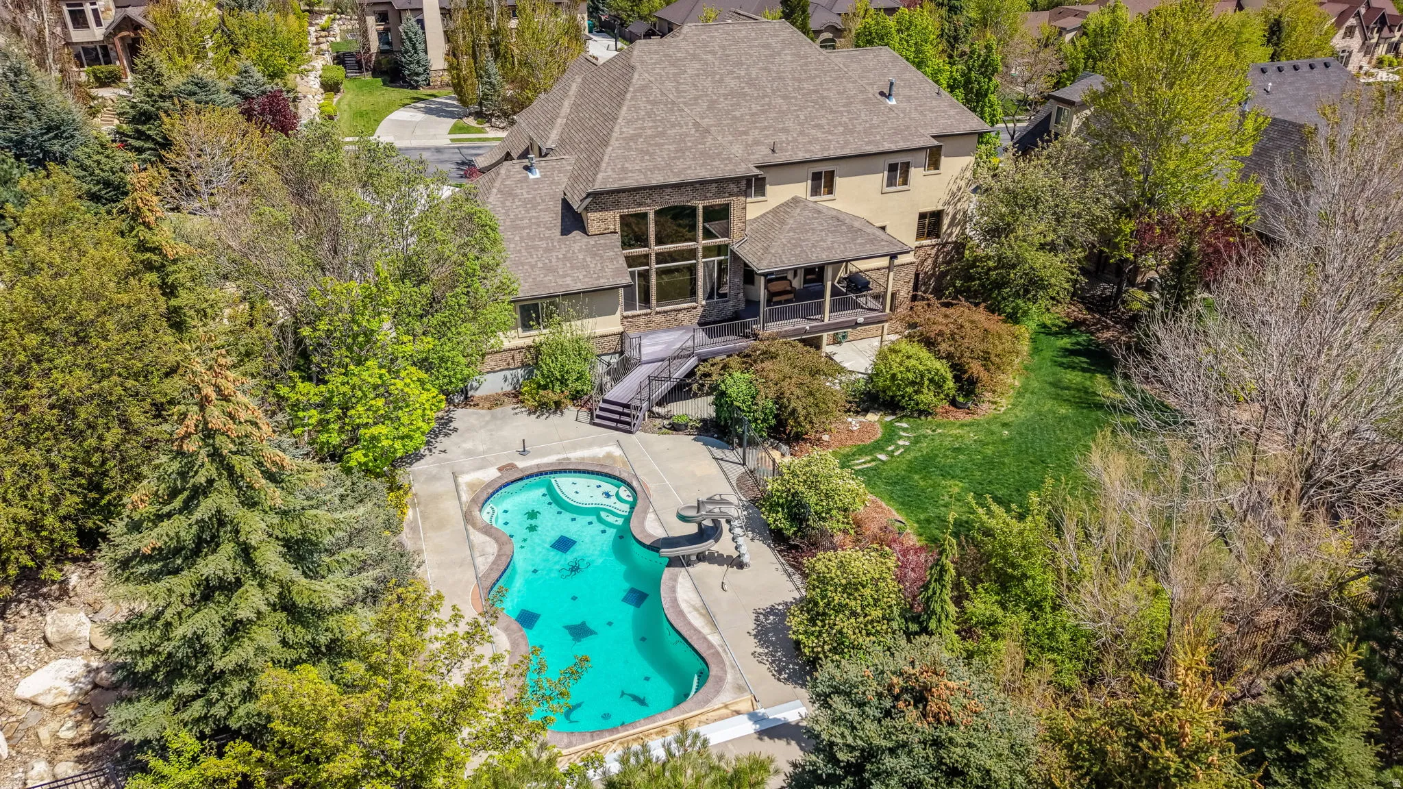 Drone / aerial view of a pool area and a tree filled landscape