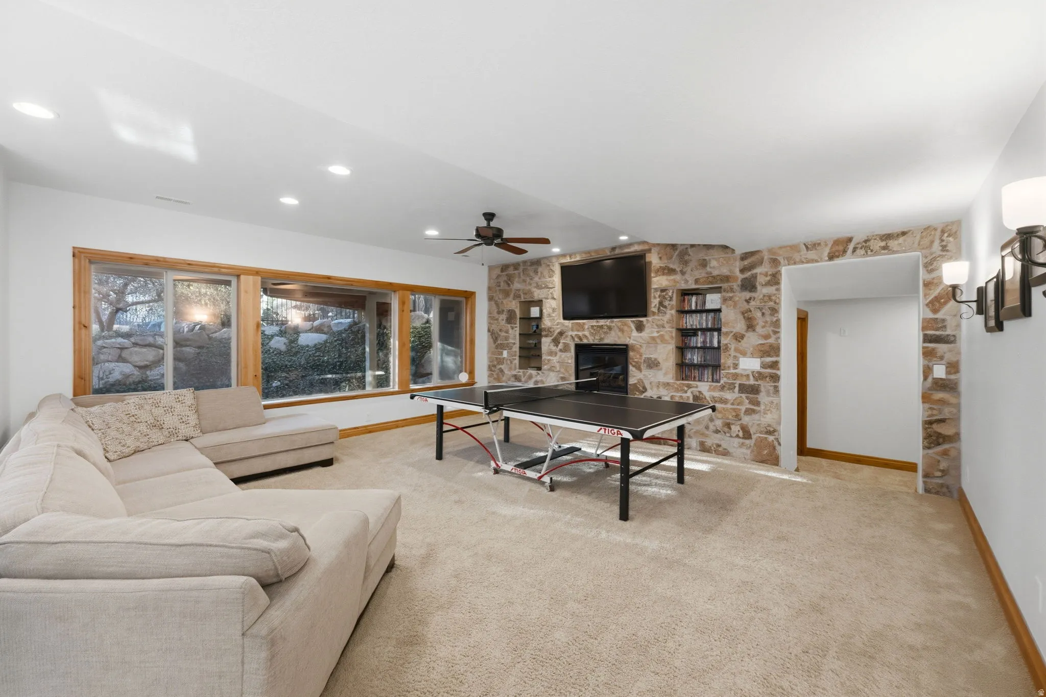Living room with a fireplace, light carpet, ceiling fan, and recessed lighting
