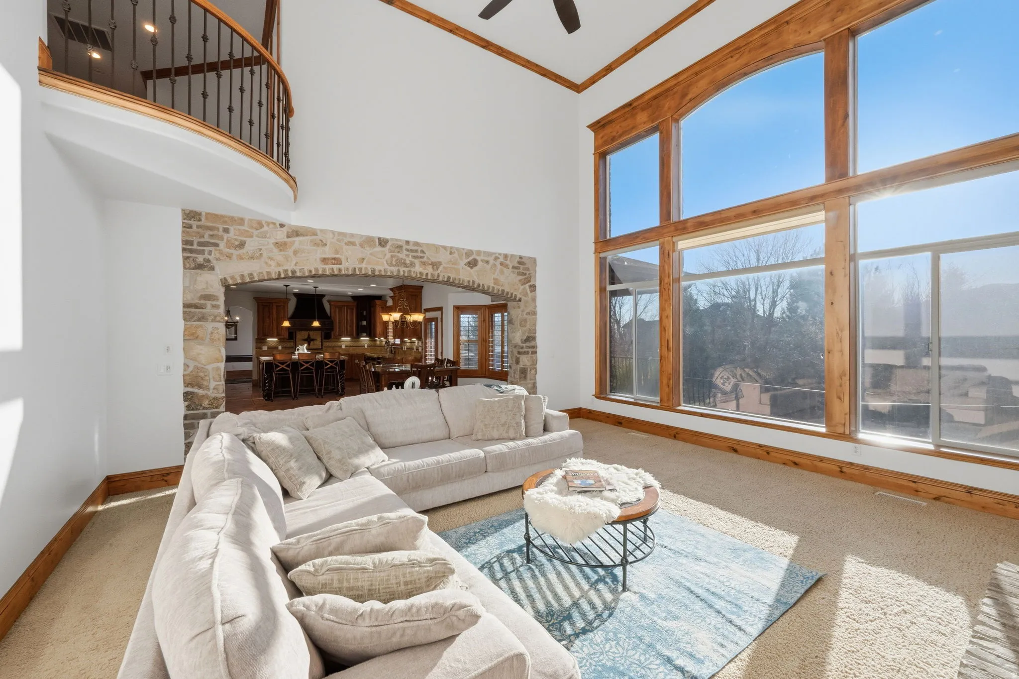 Living area with crown molding, arched walkways, a high ceiling, carpet, and ceiling fan