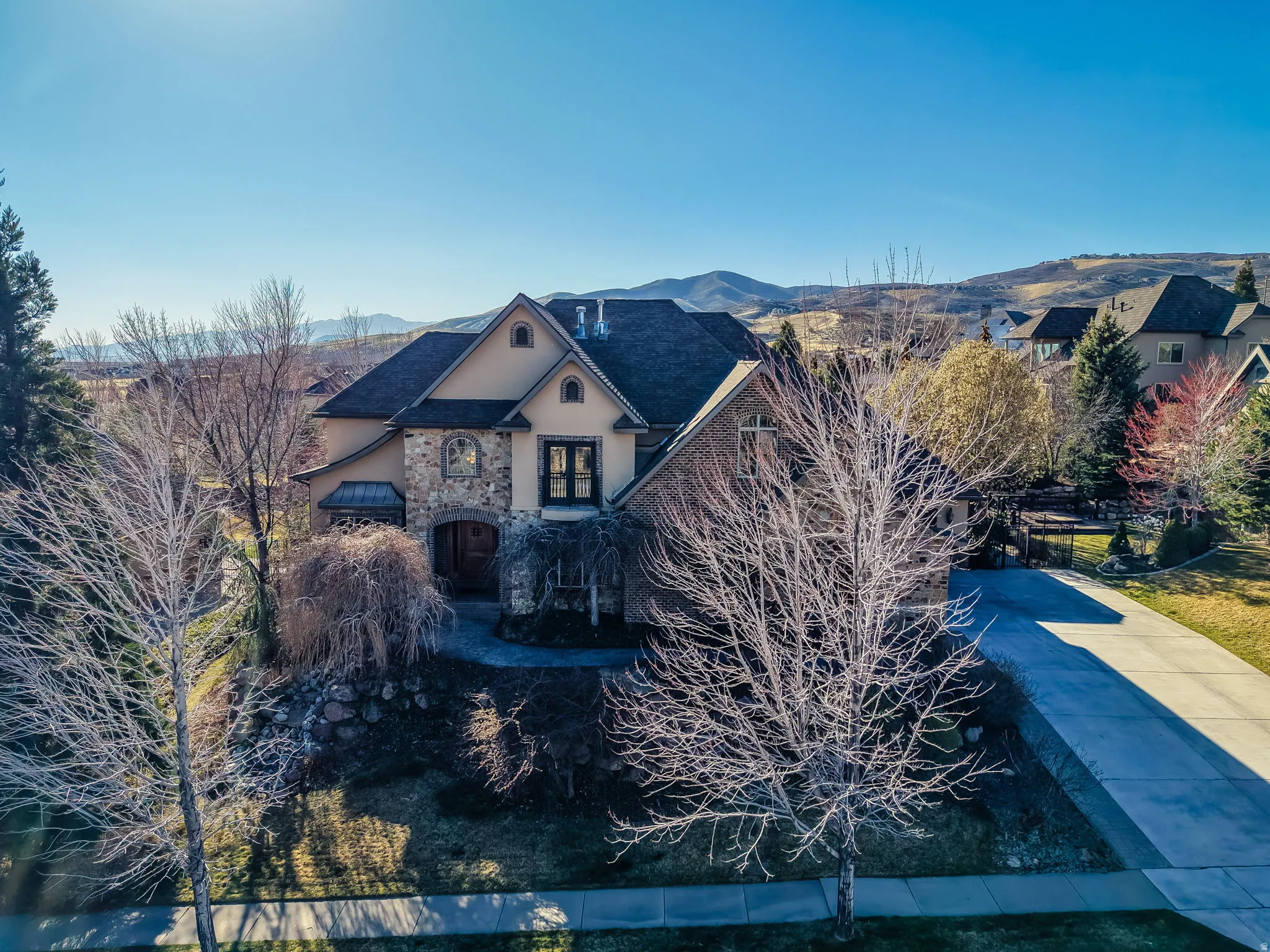 French country style house featuring stone siding, stucco siding, concrete driveway, and a mountain view
