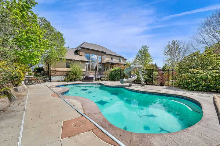 View of swimming pool with a water slide and patio surround