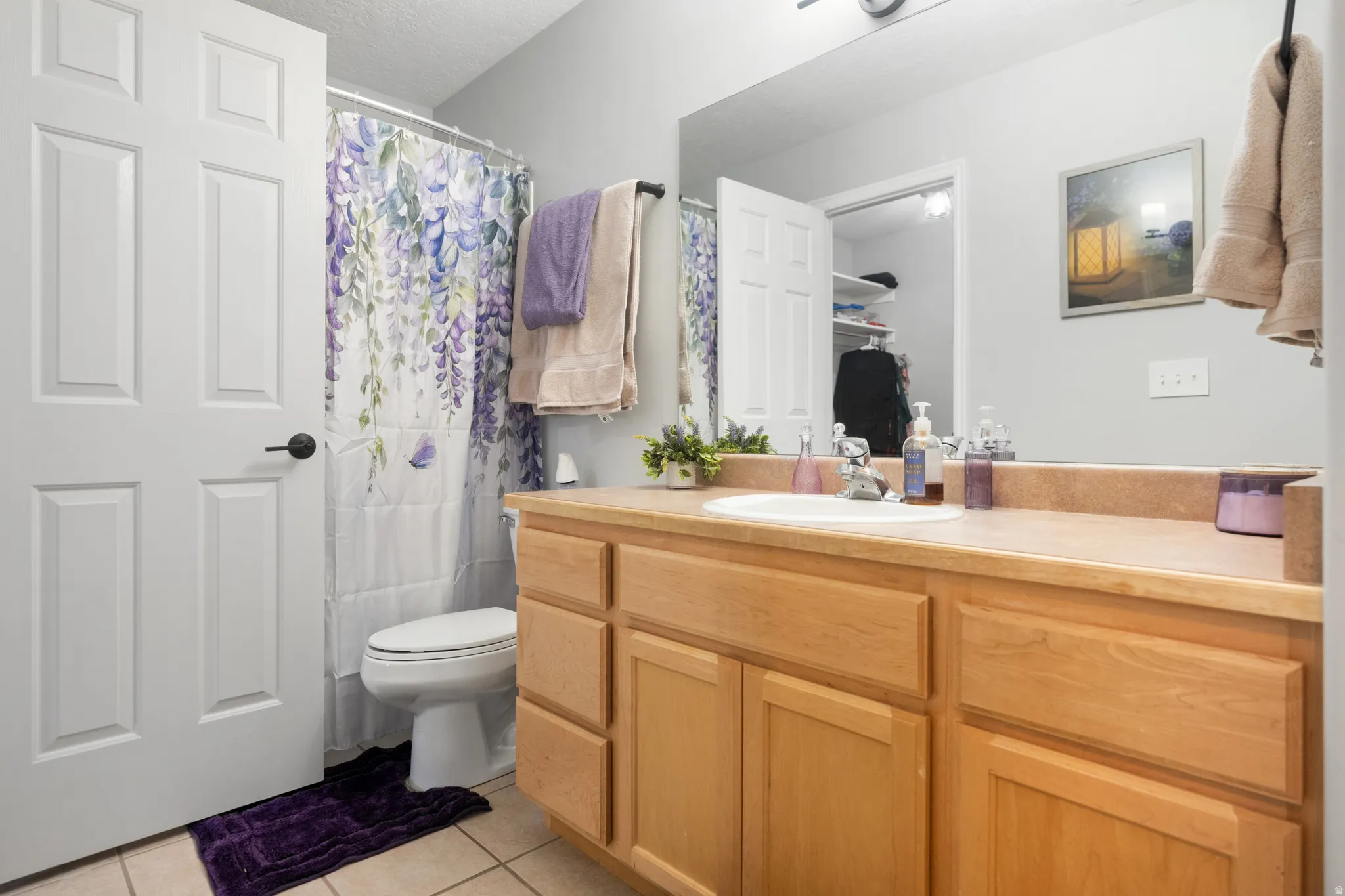 Full bath with a shower with curtain, vanity, light tile patterned flooring, and a spacious closet