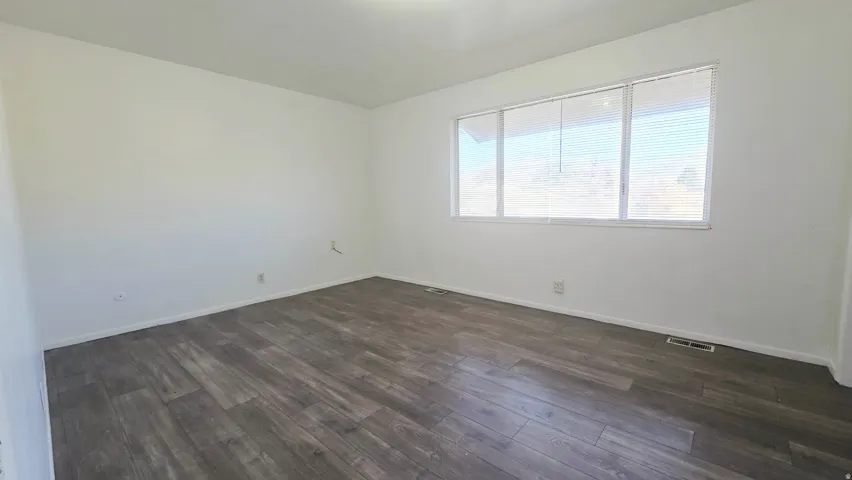 Empty room featuring dark wood finished floors and baseboards