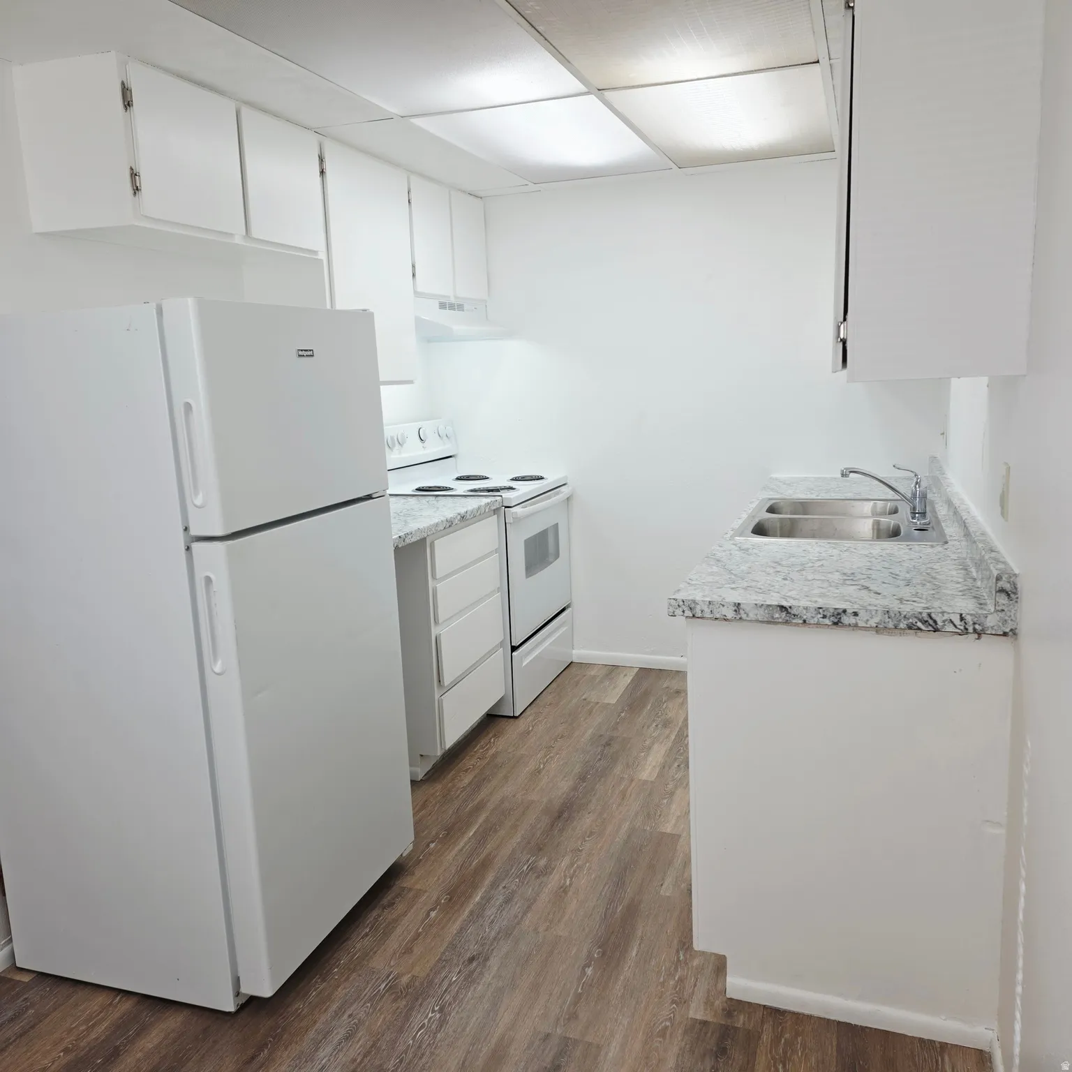 Kitchen with white appliances, white cabinetry, light countertops, and dark wood finished floors