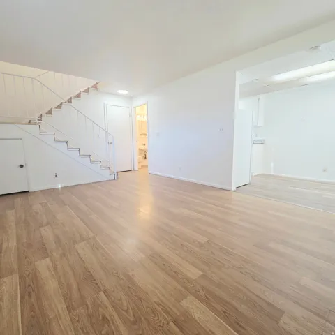 Unfurnished living room with stairs and light wood-type flooring