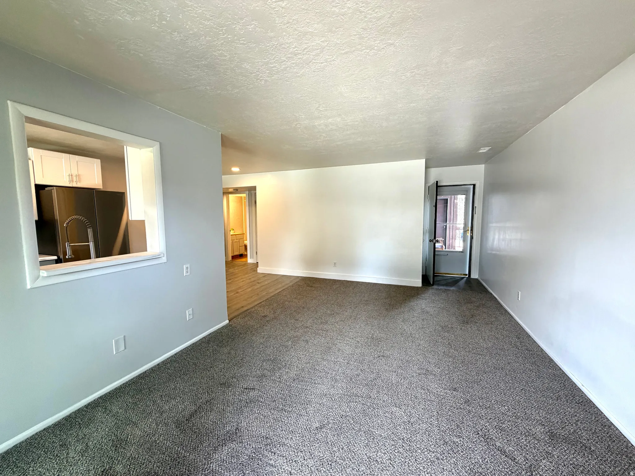 Unfurnished room featuring dark carpet and a textured ceiling