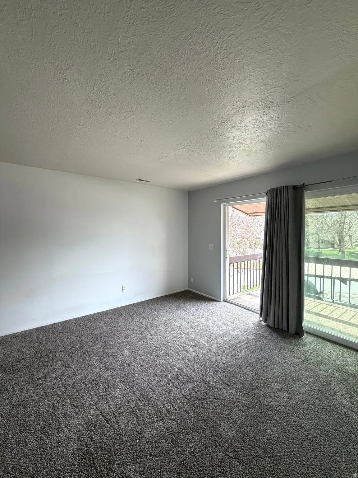 Carpeted spare room with a textured ceiling