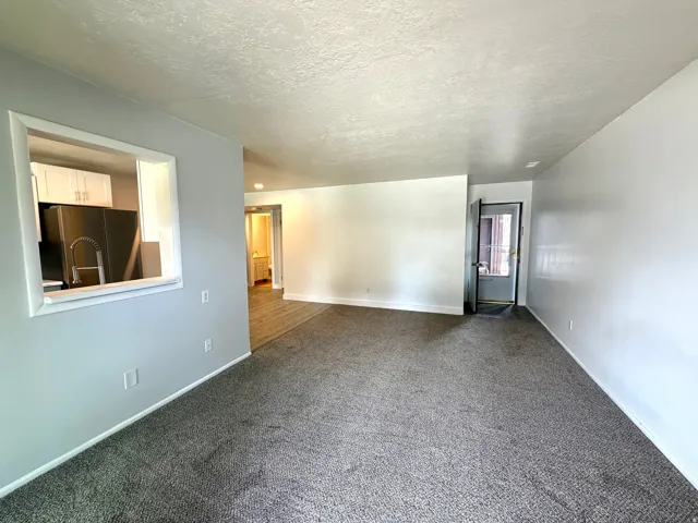 Unfurnished room featuring dark carpet and a textured ceiling