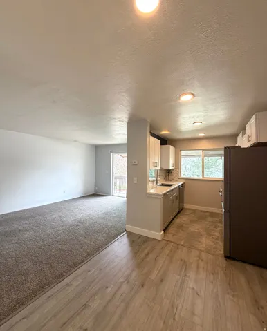 Kitchen with white cabinetry, stainless steel appliances, light countertops, open floor plan, and healthy amount of natural light