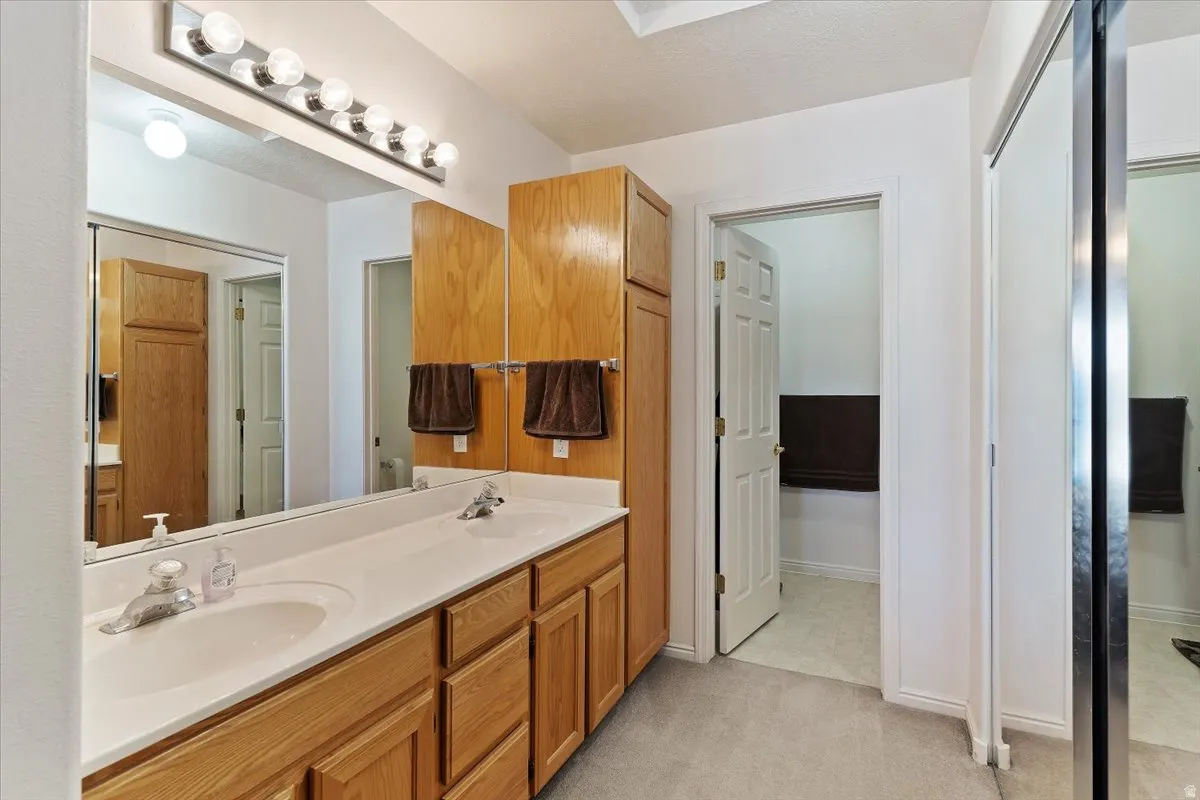 Full bathroom featuring double vanity and light carpet