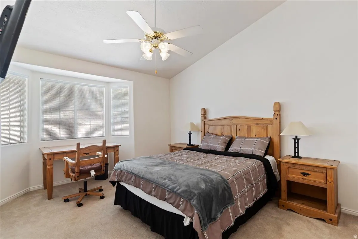 Bedroom featuring lofted ceiling, light carpet, a ceiling fan, and an office area