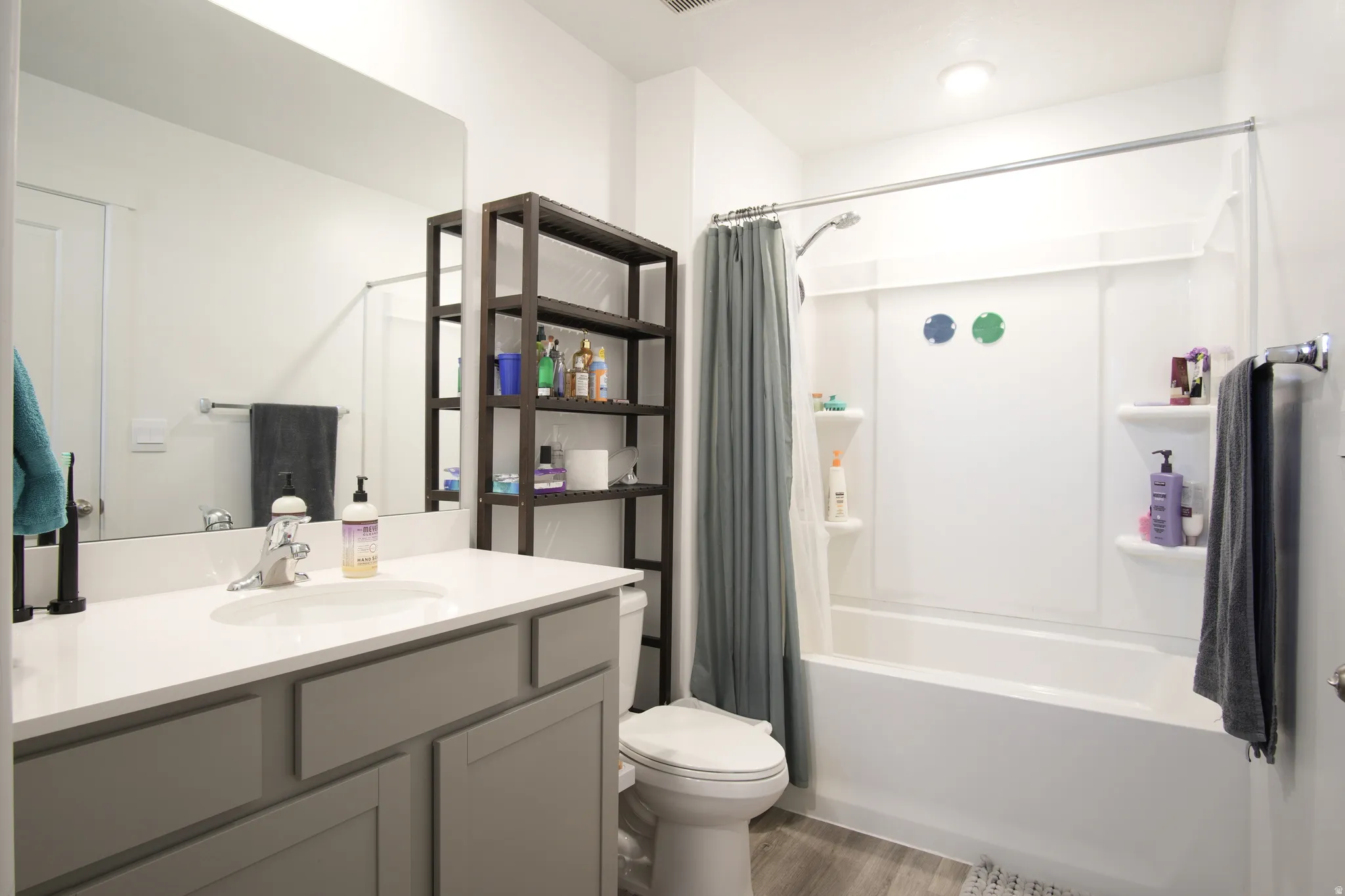 Full bath with vanity, shower / tub combo with curtain, and dark wood-style flooring