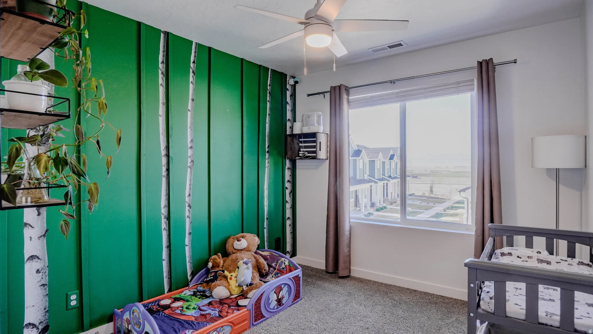 Bedroom featuring light carpet, a ceiling fan, and a crib