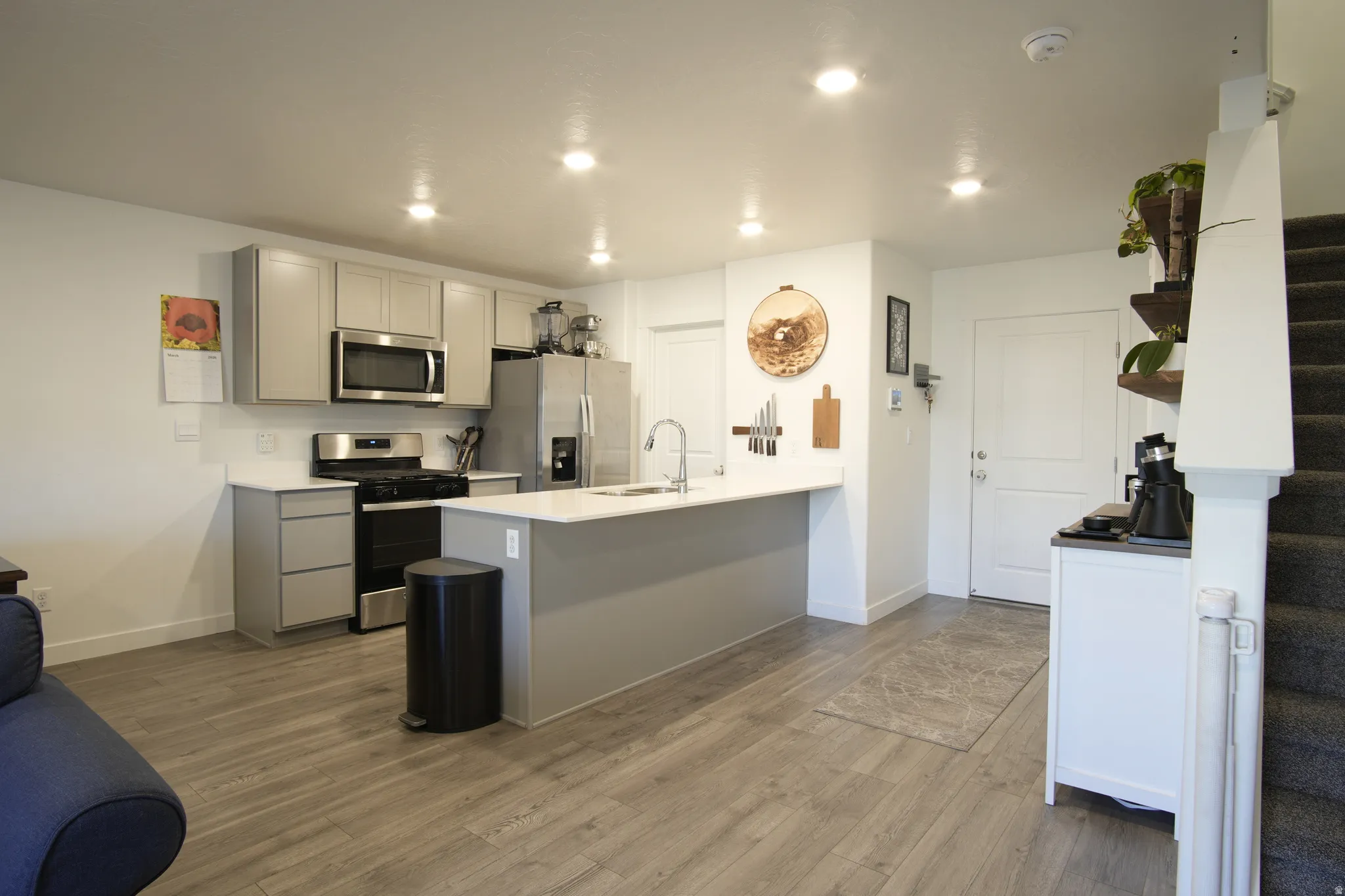 Kitchen featuring gray cabinets, stainless steel appliances, light wood-style floors, a peninsula, and recessed lighting