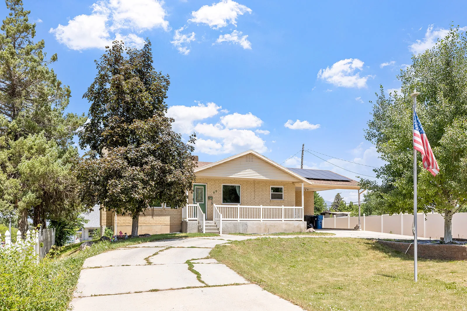View of front of property with a porch, brick siding, and roof mounted solar panels