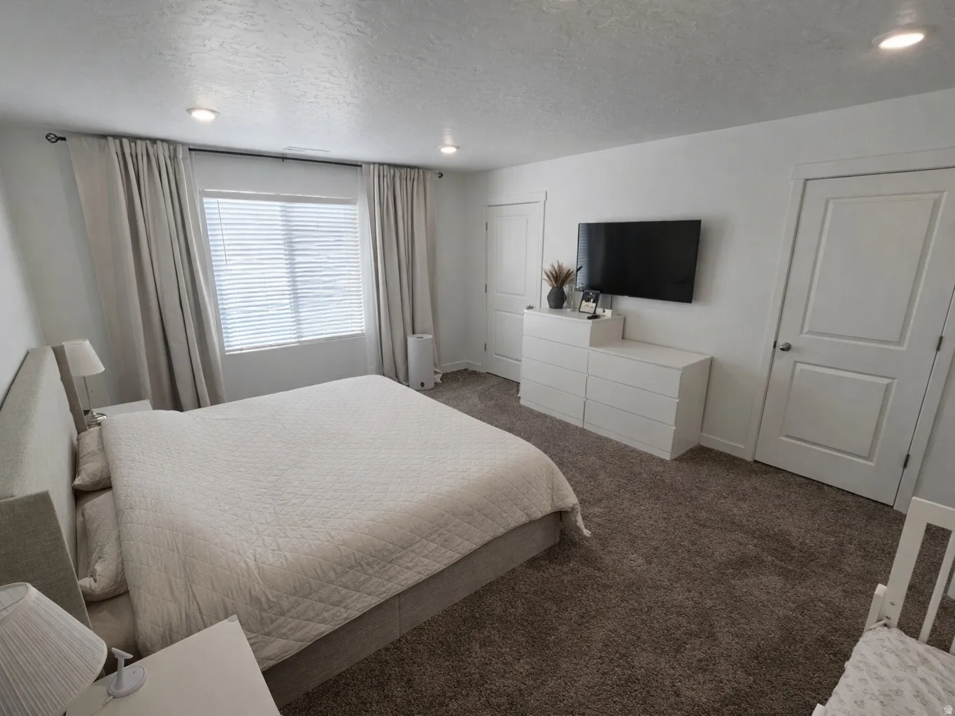 Bedroom with dark carpet, a textured ceiling, and recessed lighting