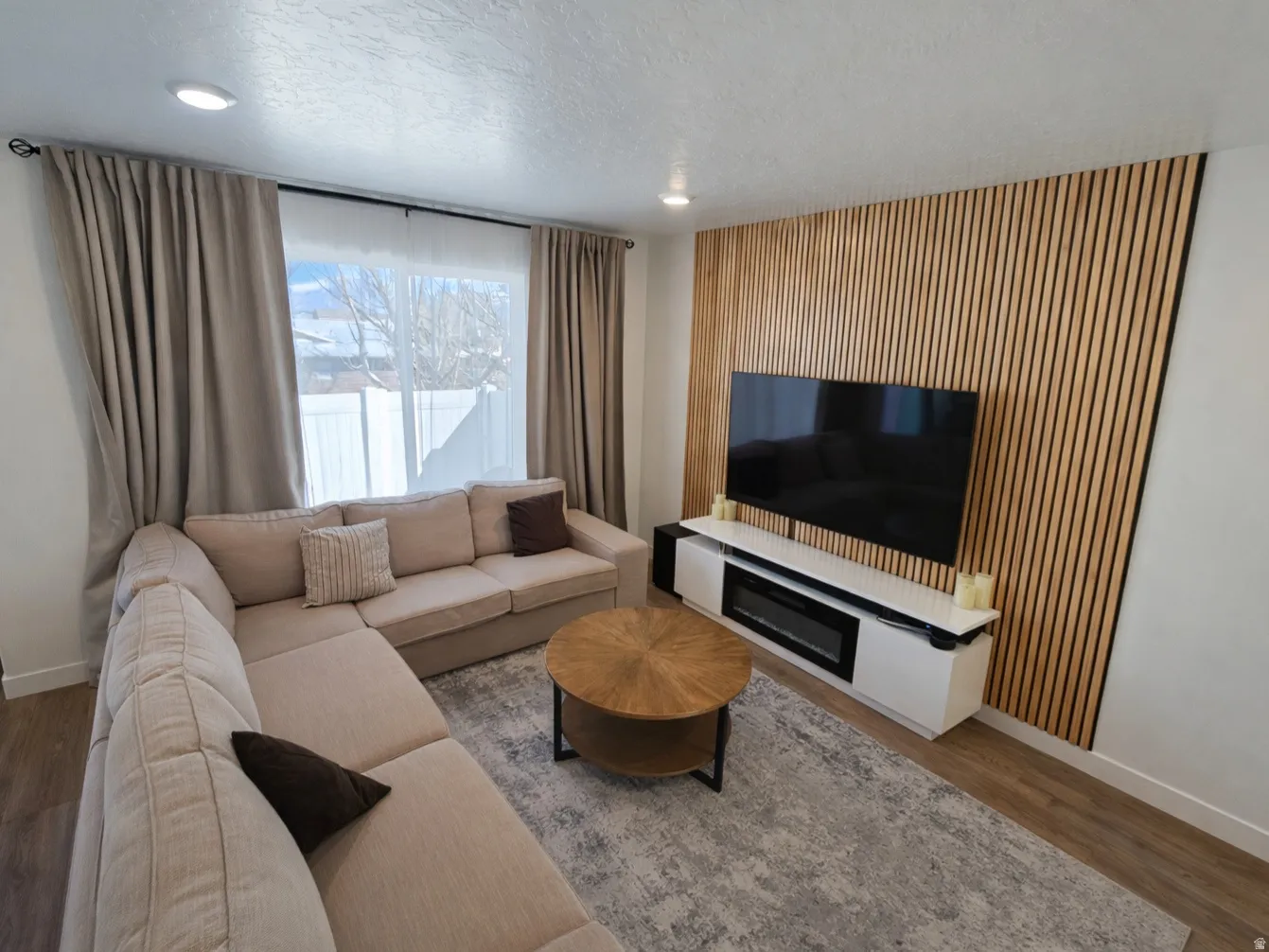 Living room featuring wood finished floors, a textured ceiling, and recessed lighting
