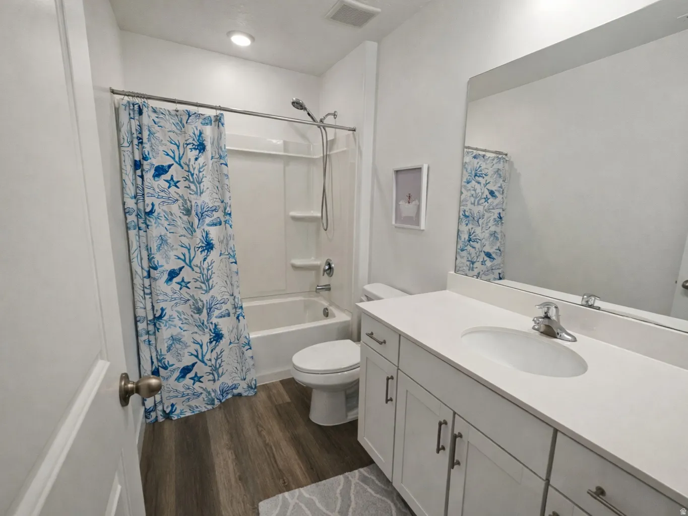 Full bath featuring dark wood finished floors, vanity, and shower / tub combo