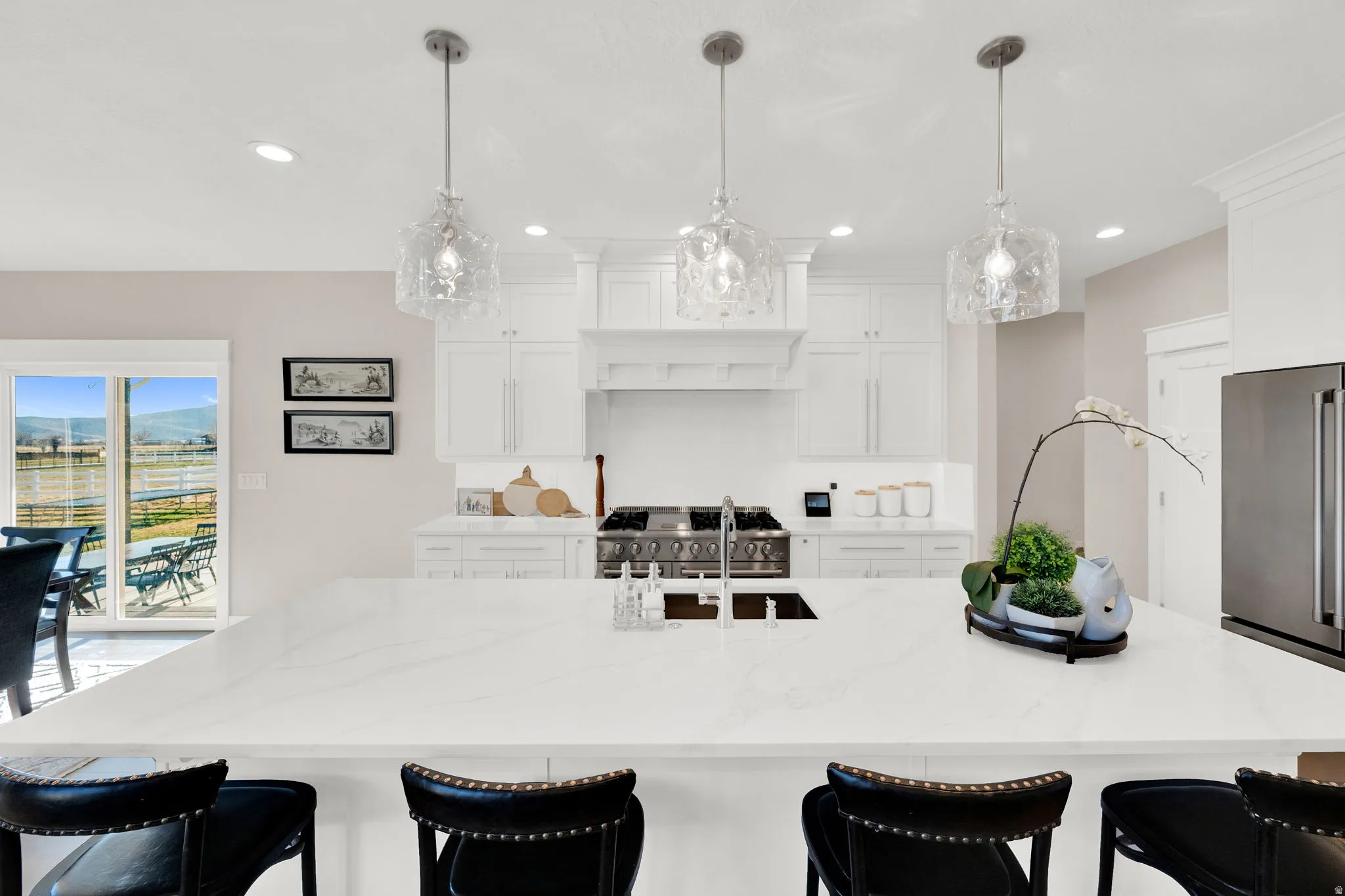 Kitchen with a breakfast bar area, a large island, light stone counters, and white cabinetry