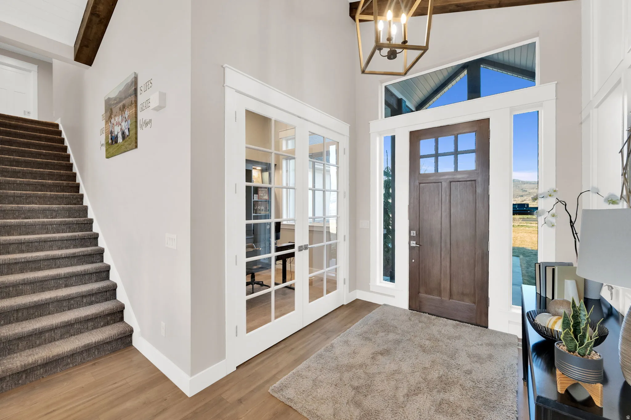 Entryway featuring vaulted ceiling, light wood-style flooring, french doors, and suspended lighting