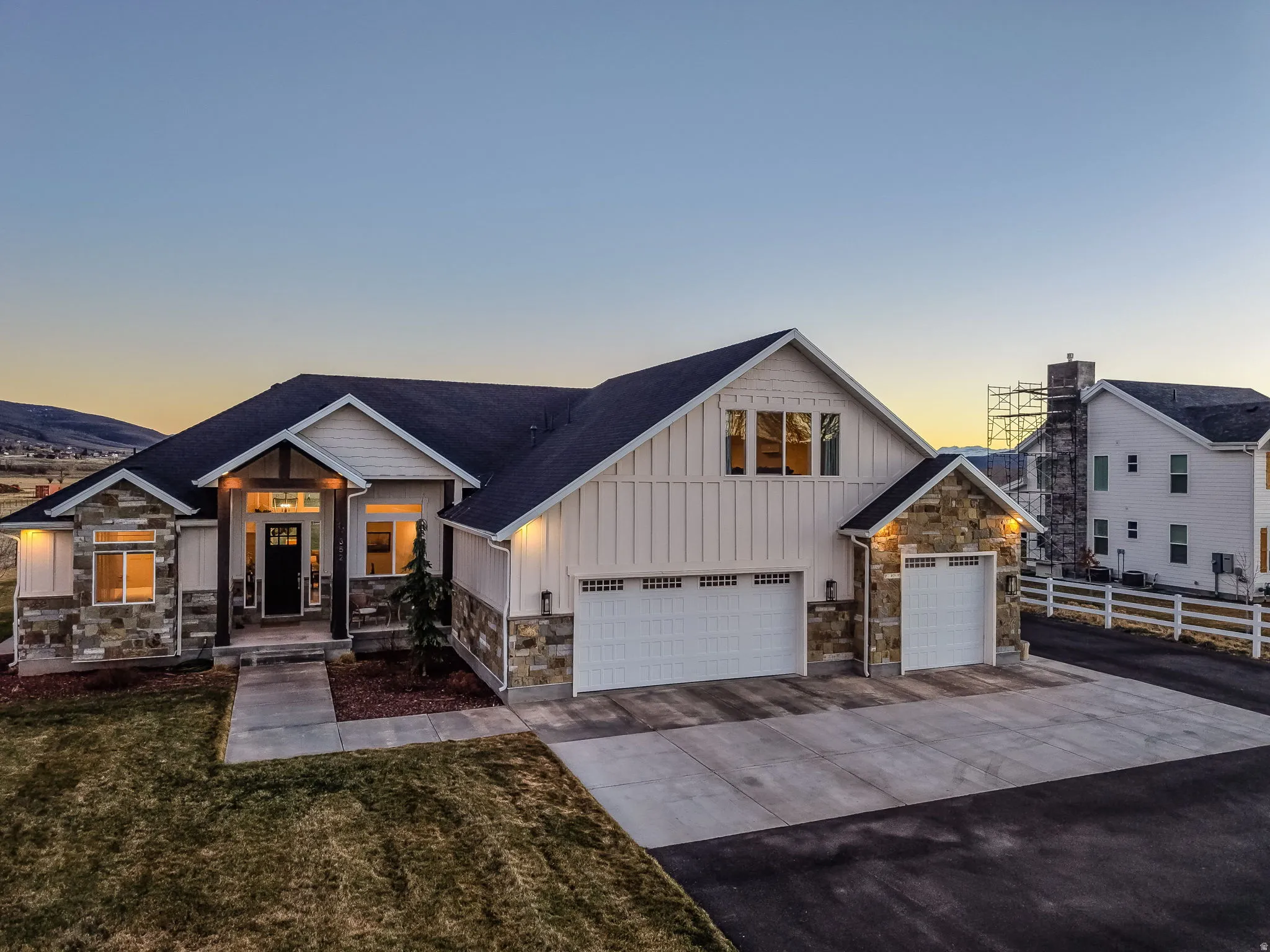 View of front of house with board and batten siding, stone siding, concrete driveway, and a garage