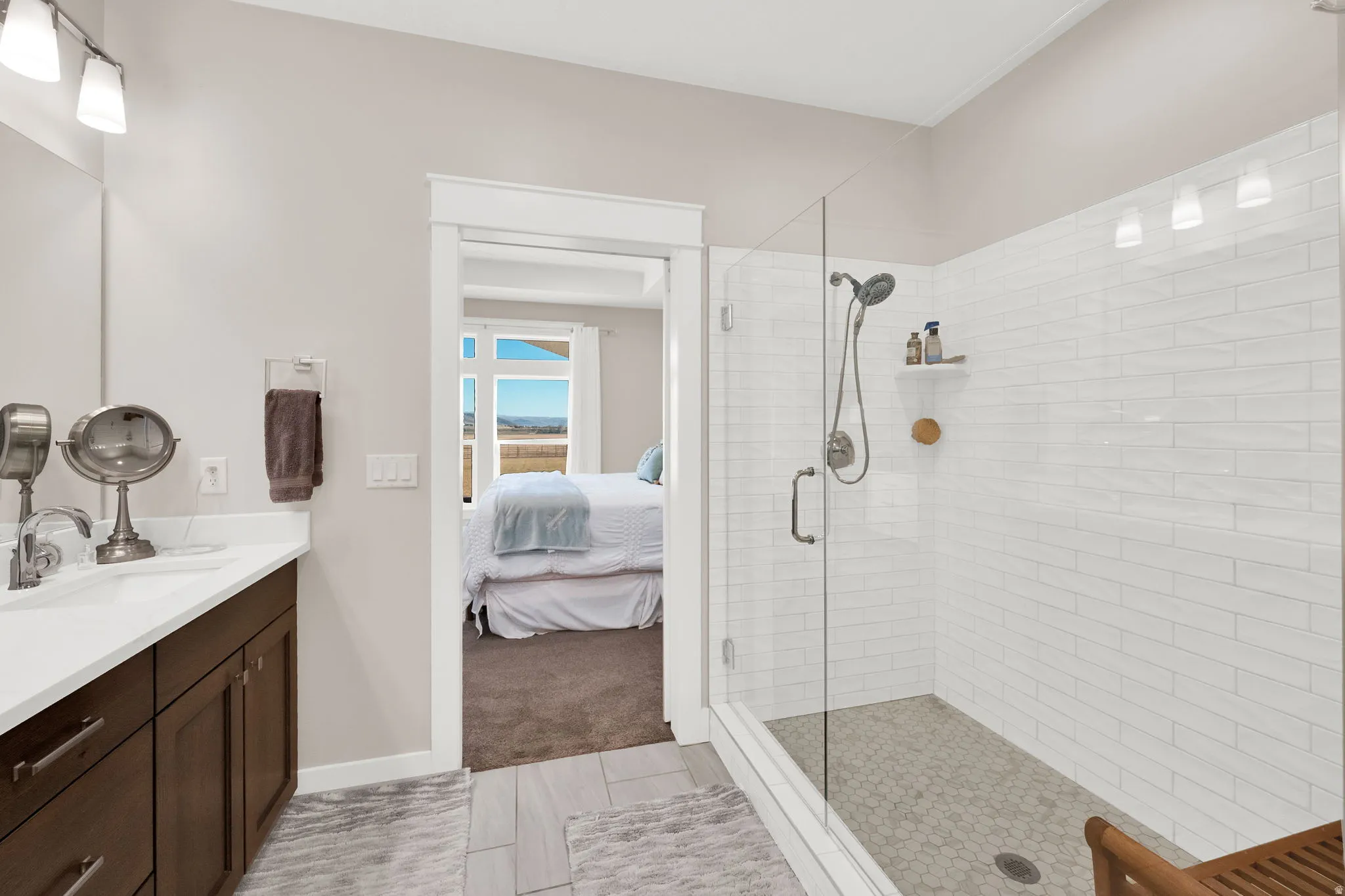 Ensuite bathroom with vanity, a shower stall, light tile patterned floors, and light colored carpet