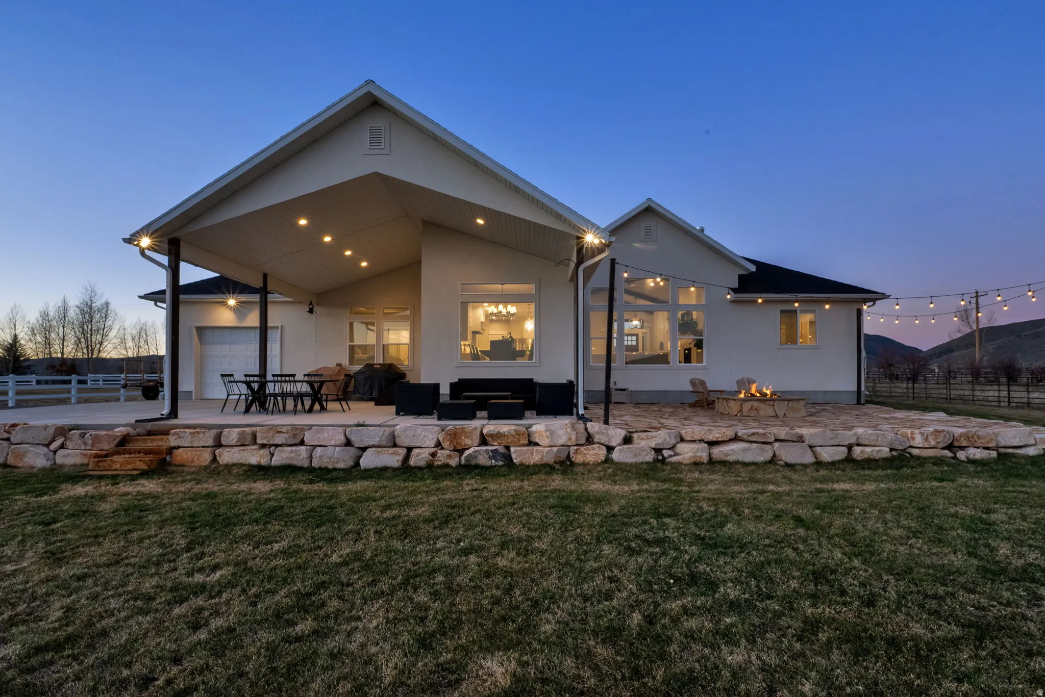 Back of property at dusk featuring a patio, stucco siding, and a garage