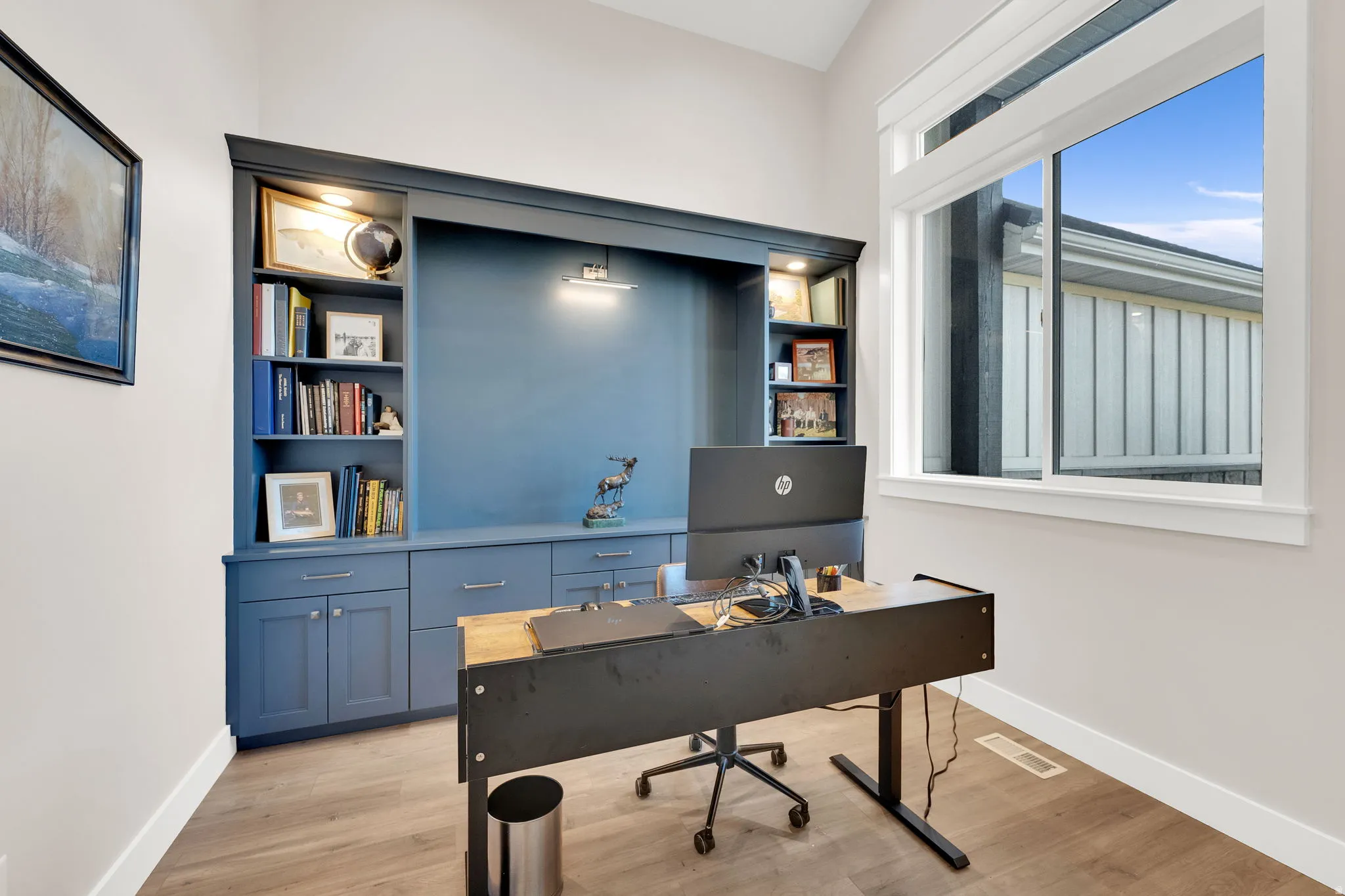 Office area featuring light wood-type flooring and built in shelves