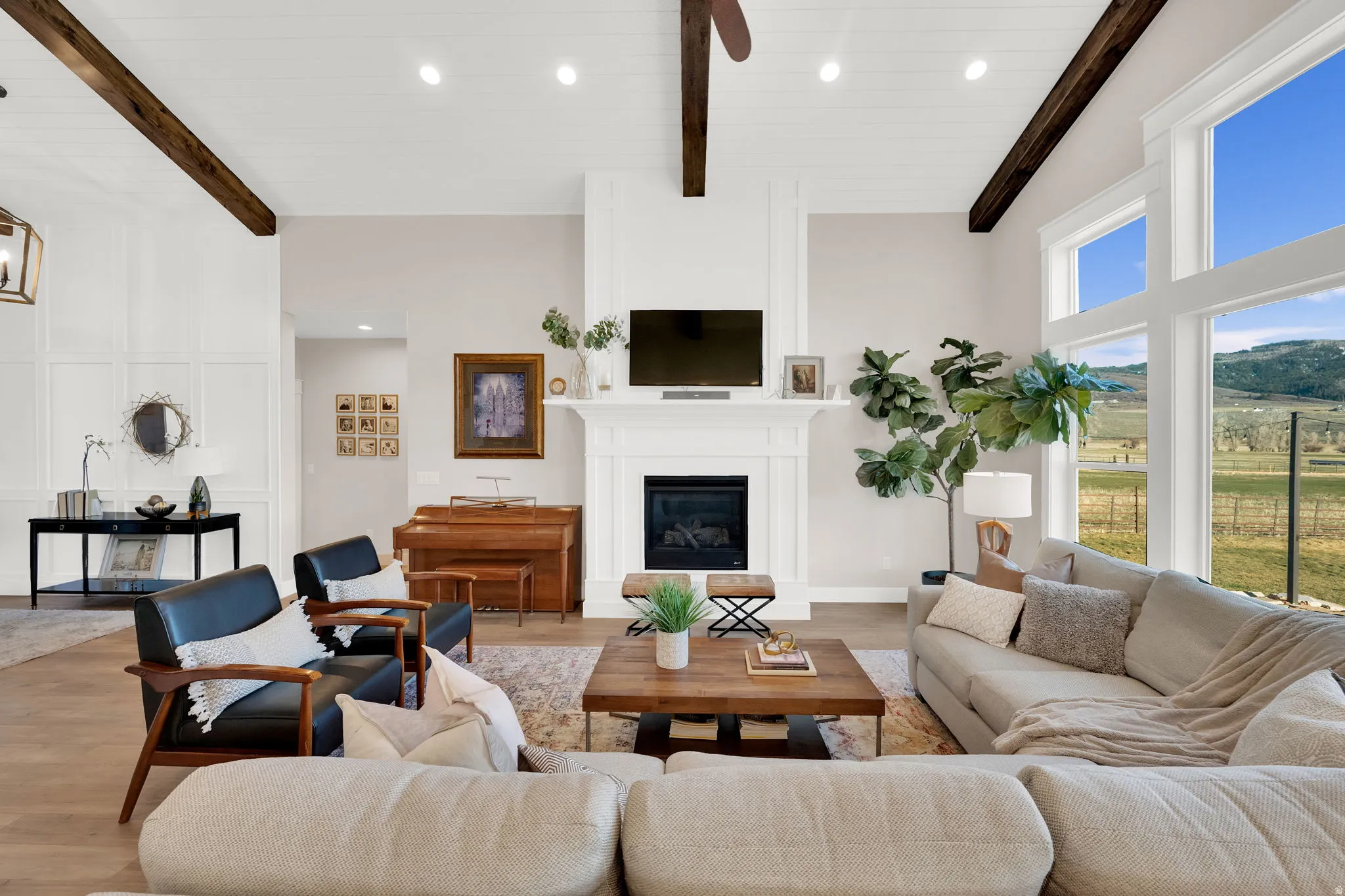 Living area with a glass covered fireplace, recessed lighting, wood finished floors, and vaulted ceiling with beams