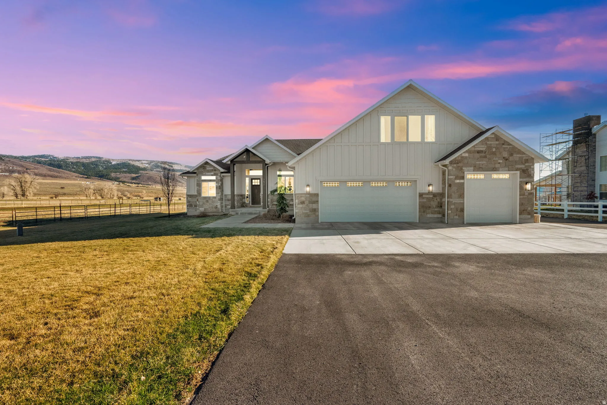 View of front of home featuring board and batten siding, driveway, stone siding, and a garage