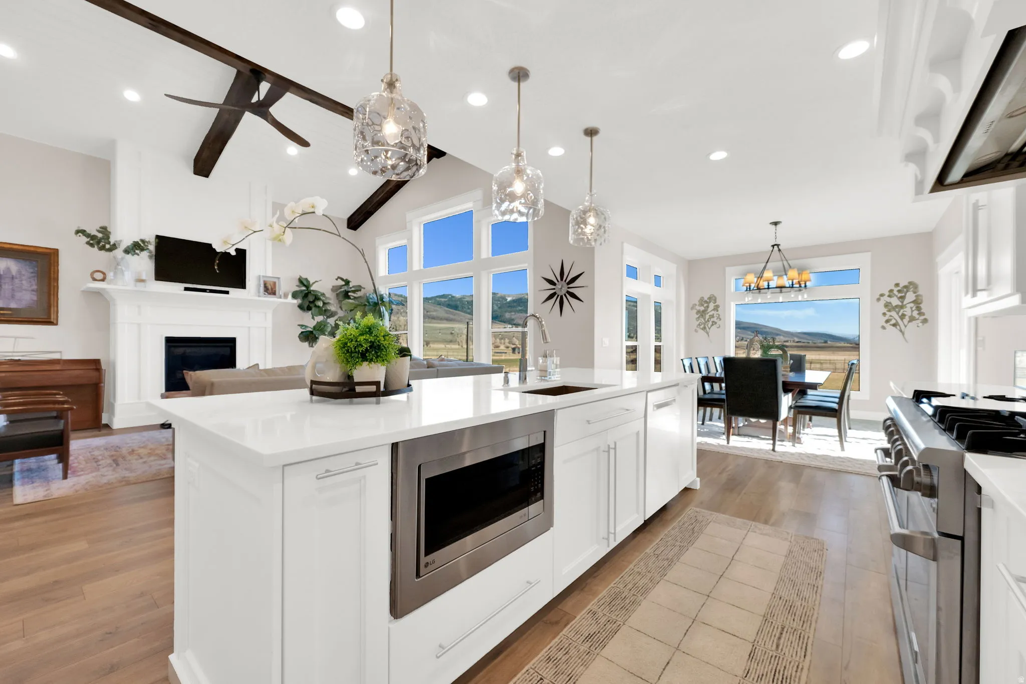 Kitchen featuring white cabinetry, range hood, a fireplace, stainless steel appliances, and vaulted ceiling