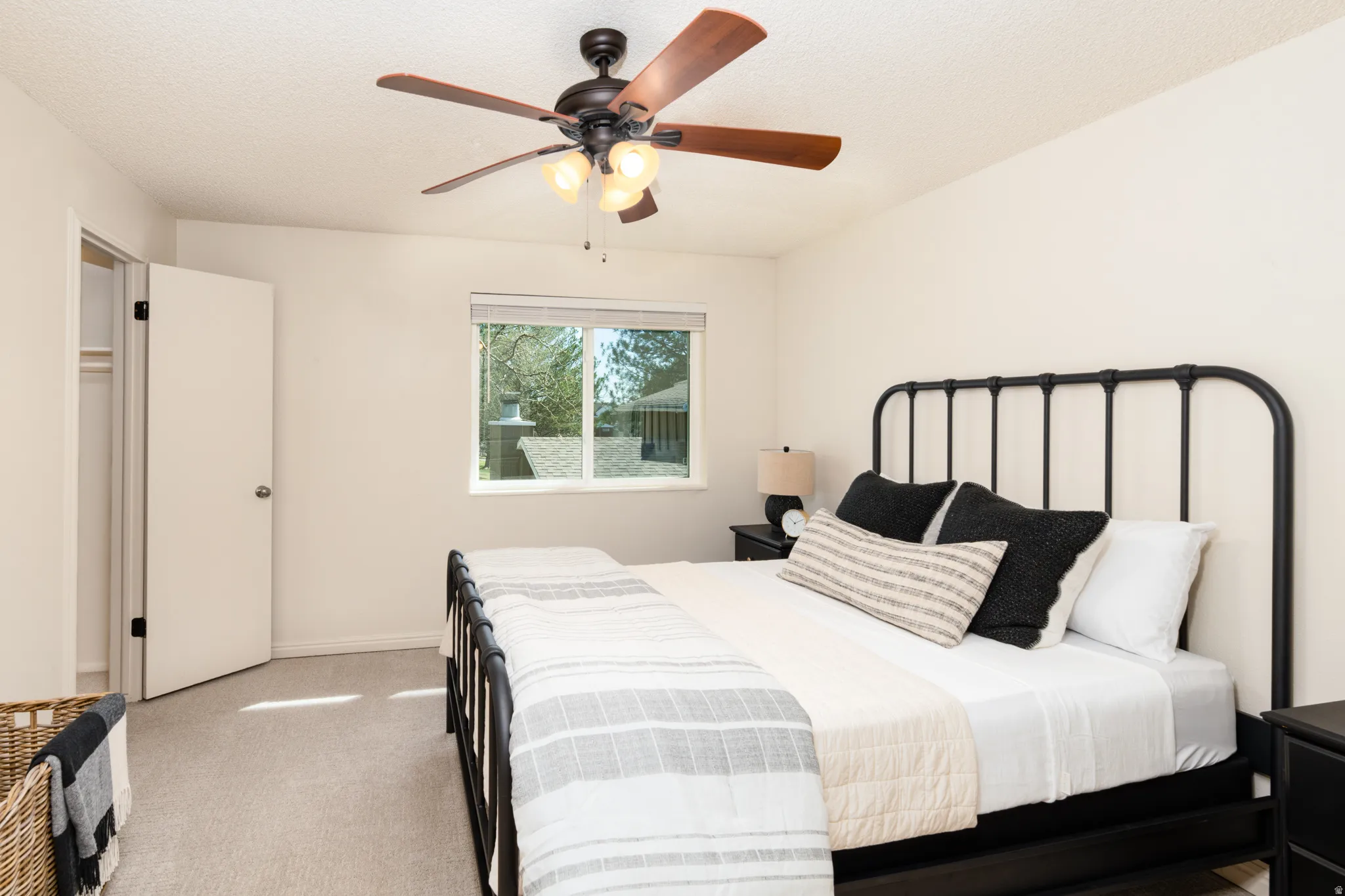 Primary bedroom with light carpet, walk in closet, and ceiling fan.