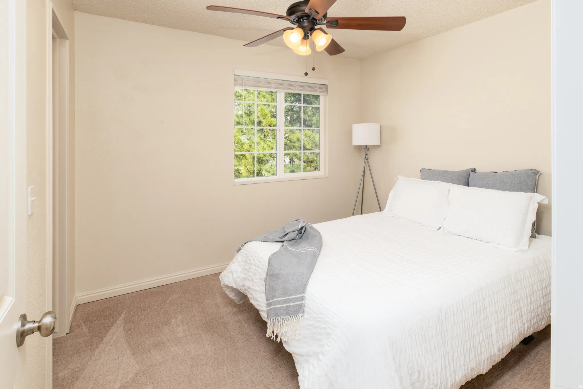 Bedroom with a walk in closet, light carpet,  and a ceiling fan.