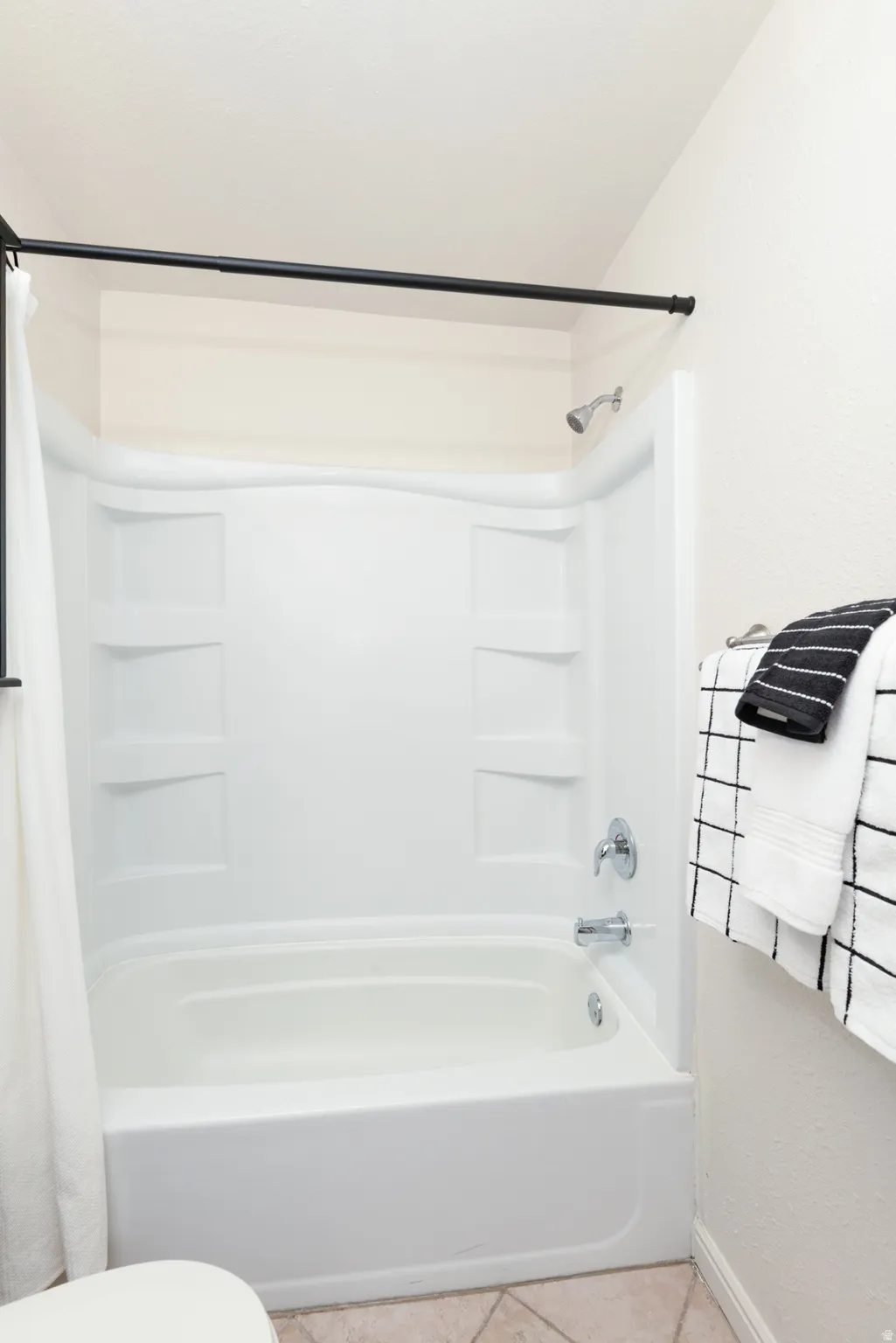 Bathroom with vanity, shower / bath combo with shower curtain, and light tile patterned floors.