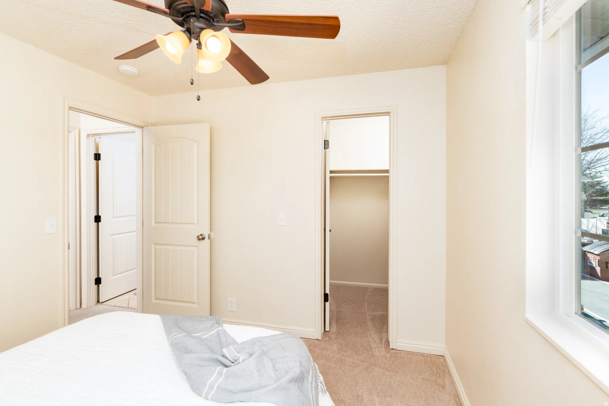 Bedroom with a walk in closet, light carpet,  and a ceiling fan.