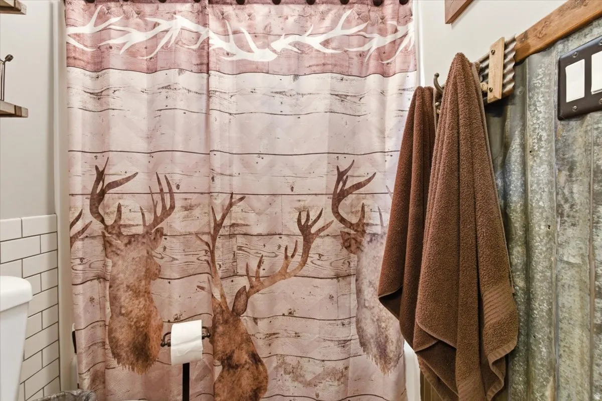 Full bathroom with a shower with curtain, tile walls, and wainscoting