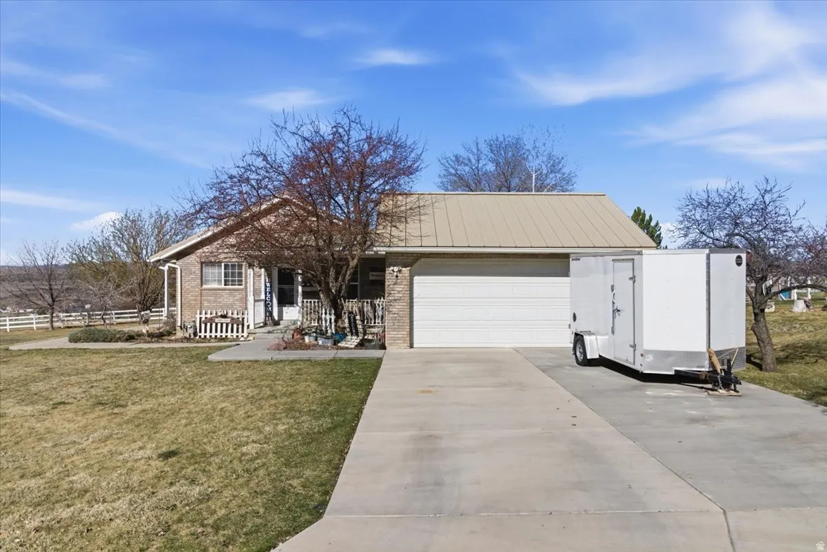 View of front of home featuring a garage, driveway, brick siding, and covered porch