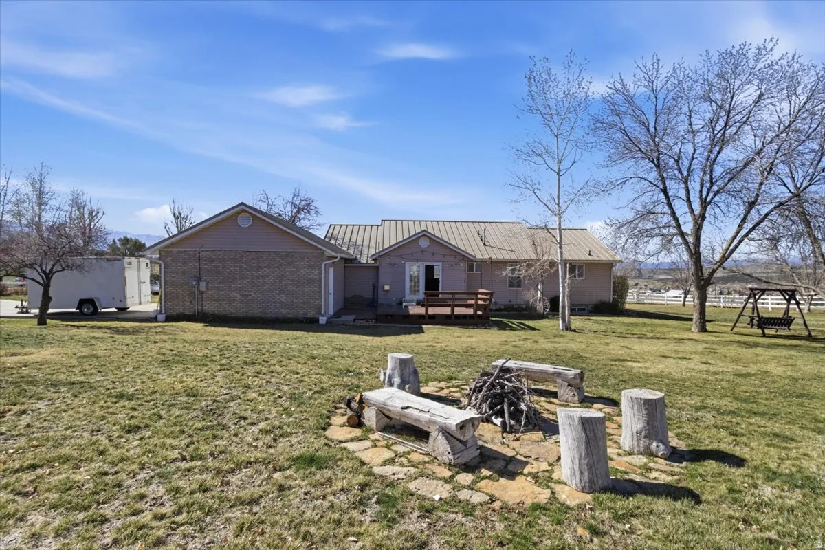 Back of house featuring a lawn, a deck, a metal roof, and brick siding