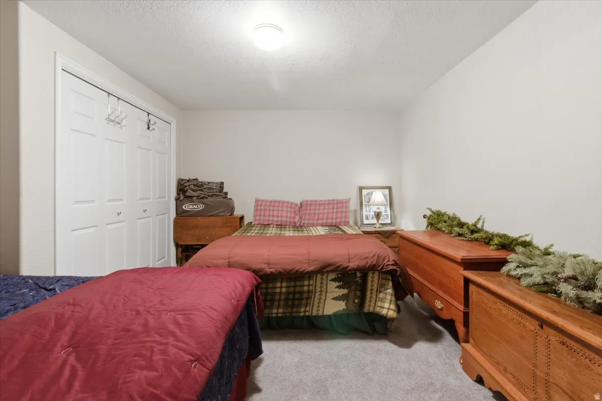 Carpeted bedroom featuring a textured ceiling and a closet