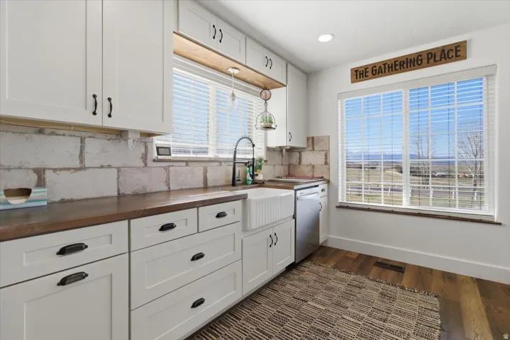 Kitchen with white cabinets, butcher block counters, dark wood finished floors, dishwasher, and backsplash