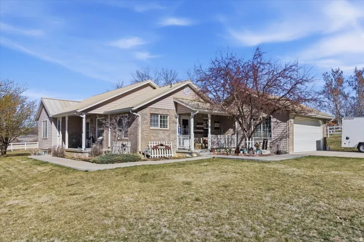 Ranch-style house with a front yard, covered porch, a garage, and concrete driveway