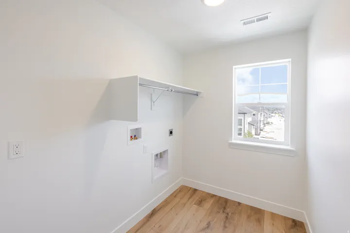 Dedicated laundry room featuring wood-finish flooring and a single window