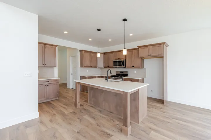 Kitchen featuring wood-finish flooring, light wood cabinetry, white countertops, and a central island with dual pendant lighting