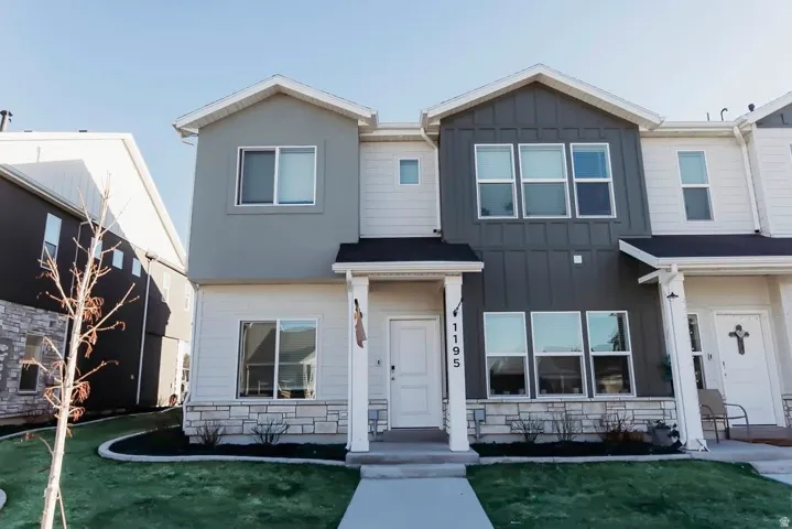 View of front facade (end unit) featuring board and batten siding, stone siding, and a front yard