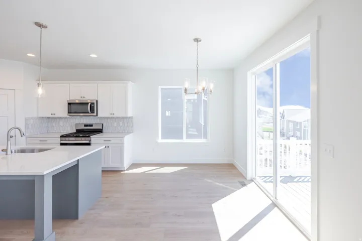 Open-concept kitchen and dining area featuring white cabinetry, a large kitchen island with a white countertop, stainless steel appliances, and wood-finish flooring