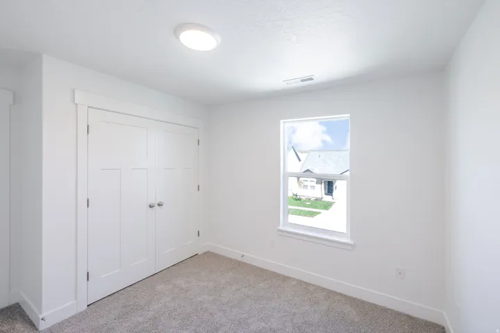 Recessed ceiling light, white paneled double doors, single pane window, neutral wall paint, and gray carpeting